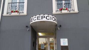 A hotel entrance with a reception sign, double doors, and a staircase leading up.
