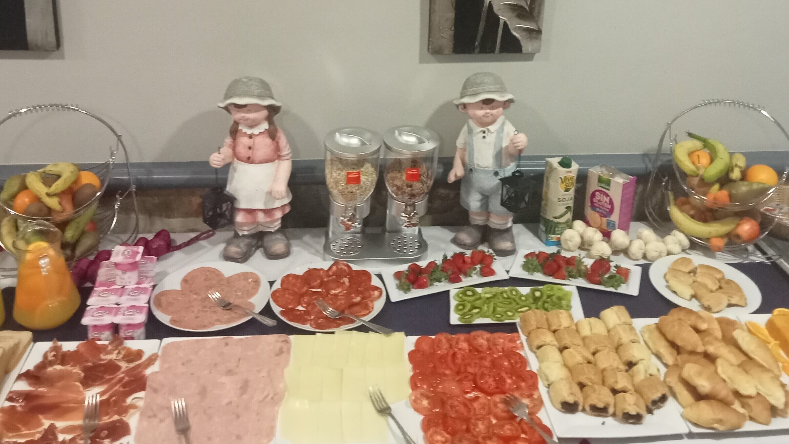 Une table de buffet proposant une variété d’aliments, notamment des viandes, des fromages, des fruits et des légumes.
