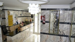 A lobby with a reception desk, a fire extinguisher, a large mirror, and a marble floor. - El pozo de la Nieve (Tordesillas)