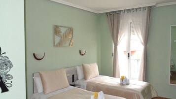 Una habitación con dos camas, un cuadro en la pared y una ventana con cortinas.