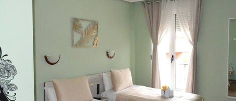 Une chambre avec deux lits, un tableau au mur et une fenêtre avec des rideaux.