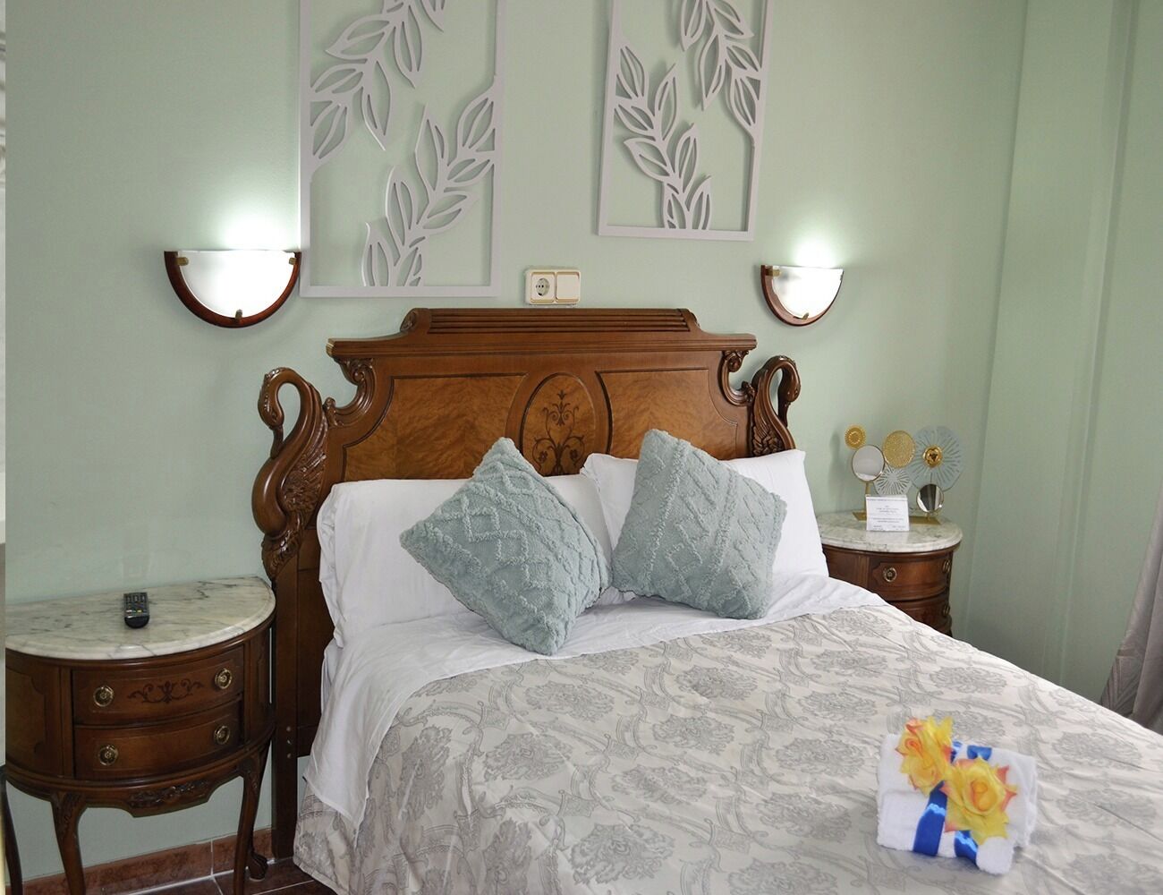 Un lit avec une tête de lit en bois, deux tables de chevet et des appliques murales.