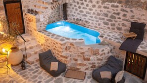 A stone-walled outdoor hot tub area with seating and a wooden door. - Dandy Villas Tower-Built in 17th century (East Mani)