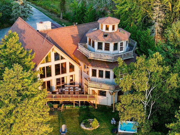 A large, multi-story house with a prominent tower, a deck, and a swimming pool.