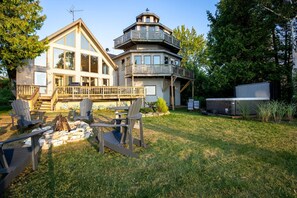 A two-story house with a deck and a fire pit in the backyard.