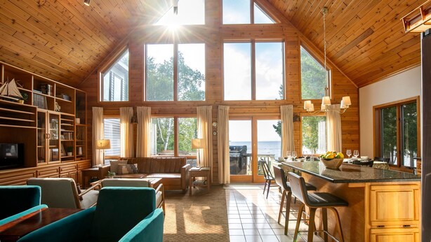 A spacious living area with a high ceiling, large windows, and a view of the outdoors.