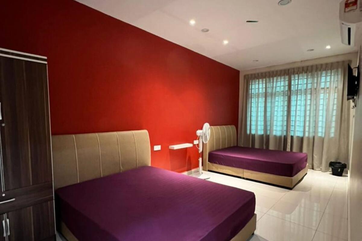 Ein Hotelzimmer mit zwei Betten, einem Schrank, einem Schreibtisch und einem Fenster mit Vorhängen.