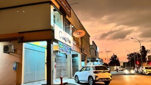 Une vue d’une rue au crépuscule, avec un bâtiment portant les inscriptions « Alma Sweet Home » et « Orange Point ».