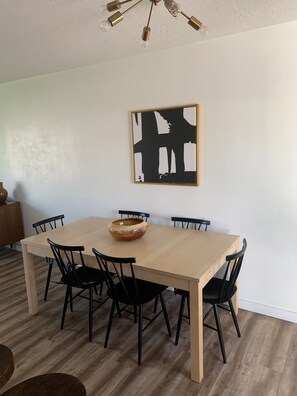 A dining area with a wooden table, six chairs, and a hanging light fixture. - Experience the Best of Provo and Orem at Our Stylish and Comfortable VRBO. (Orem)
