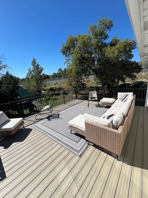 A deck with wicker furniture, a patterned rug, and a view of the surrounding landscape.