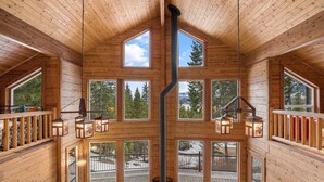 Una cabaña de troncos con varias ventanas, chimenea y techo de madera.