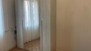 A room with a large mirror, a door, and a tiled floor.