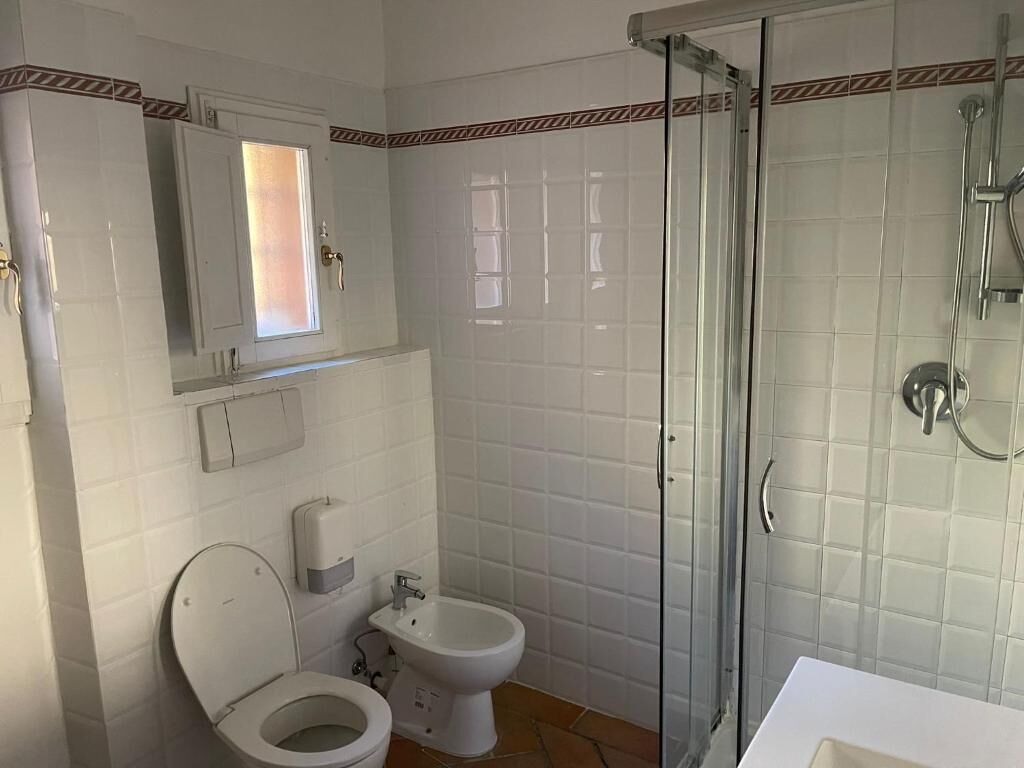 A bathroom with a toilet, bidet, and a glass-enclosed shower area.