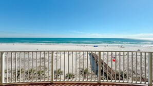 A beach view from a balcony with a railing, ocean, and a few people in the distance. - 3rd Floor!! New Owner, Zero Entry Pool w/ Slide!! (Gulf Shores)