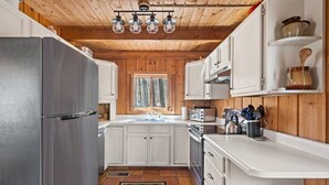 Una cucina moderna con mobili bianchi, un frigorifero in acciaio inossidabile e una finestra che fa entrare luce naturale.