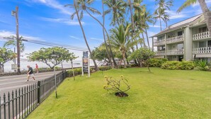 A hotel with a balcony, a grassy lawn, and palm trees. - Nautical Theme Garden View Studio - Kona Islander Inn Condos Condo by RedAwning (Kailua-Kona)