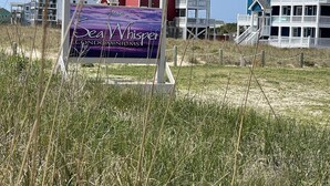 A sign for 'Sea Whisper Condominiums' with a view of beachfront buildings. - Sw 3 Finns Up 1 Bedroom Condo by RedAwning (Hatteras)