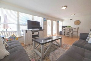 Una sala de estar con un sofá, una mesa de centro, un televisor y un comedor con sillas y una mesa.