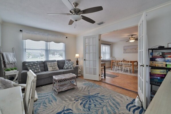 A living room with a grey sofa, patterned cushions, a coffee table, and a ceiling fan.
