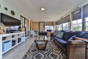 A living room with a sofa, coffee table, TV, and a bookshelf.