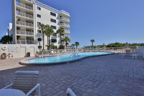 A swimming pool area with lounge chairs and a building with balconies. - 5301 Shorehom By The Sea 73 2 Bedroom Condo by RedAwning (New Smyrna Beach)