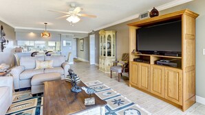 A living room with a sofa, coffee table, and a TV stand. - Recently Renovated Beach Condo with Large Patio Deck and Ocean View by RedAwning (Fernandina Beach)