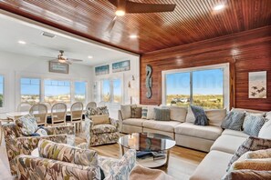 A spacious living room with a wooden ceiling, large windows, and a variety of seating options including a sofa and chairs. - Dog Friendly Beachfront Condo, Direct Access to Beach by RedAwning (Fernandina Beach)