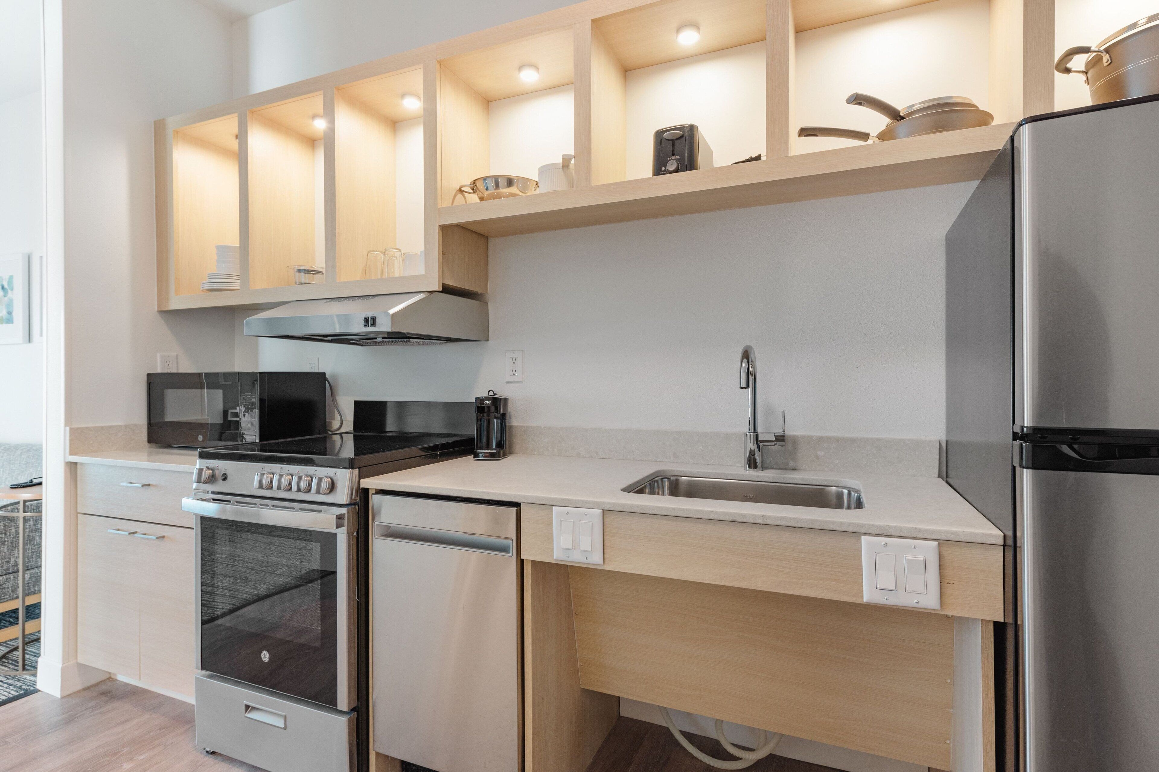 A modern kitchen with stainless steel appliances, wooden cabinets, and a built-in microwave.