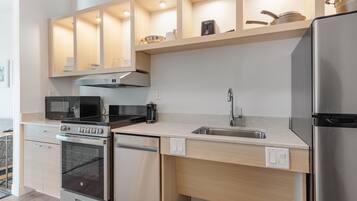 A modern kitchen with stainless steel appliances, wooden cabinets, and a built-in microwave.