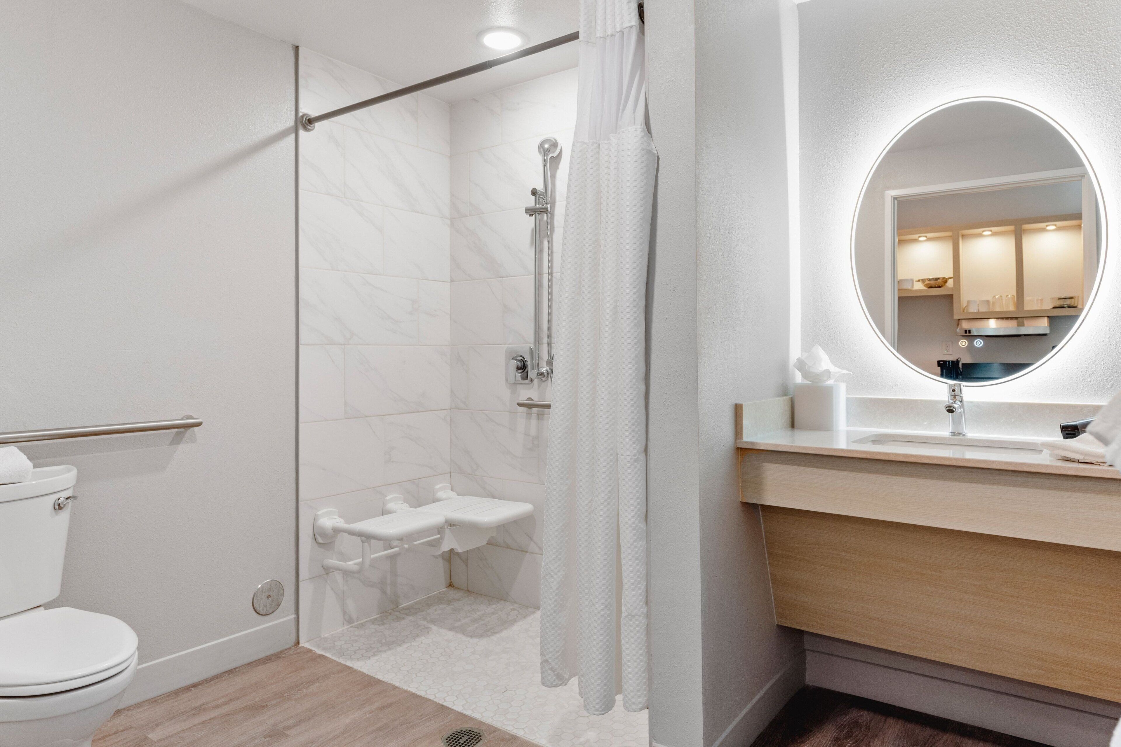 A modern bathroom with a glass-enclosed shower, a white toilet, a sink with a mirror, and a wooden vanity.