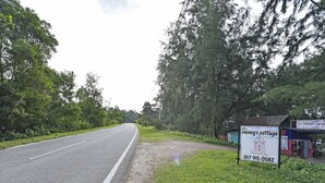 A road leading to a cottage with a signboard advertising 'The Sibling's Cottage' and a contact number.