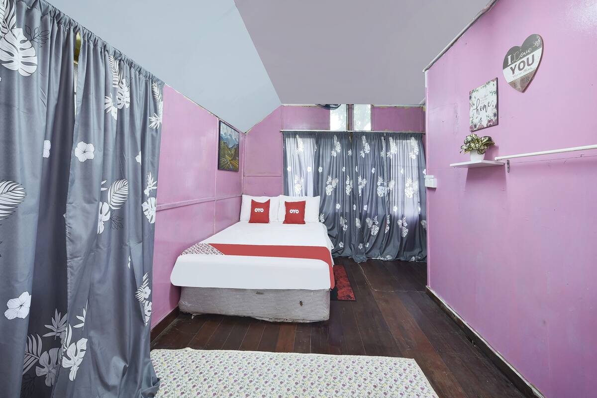 Un dormitorio con una cama, cortinas, un estante con una planta y una decoración con forma de corazón en la pared.