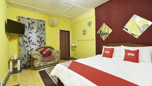 Una habitación de hotel con una cama, un sofá, un televisor y un ventilador de pared.