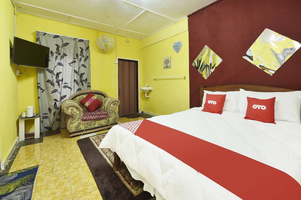 Una habitación de hotel con una cama, un sofá, un televisor y un ventilador de pared.