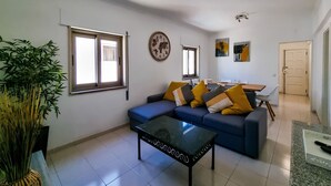 Un saló amb un sofà, una taula de centre i una zona de menjador amb cadires i una taula.