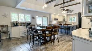 Una cocina amplia con armarios blancos, un comedor con sillas de madera y una isla grande con un lavamanos.