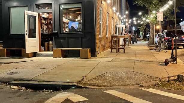 A brick building with a storefront, outdoor seating, and a crosswalk. - Entire Unit-5min to M&TBank Camden Yards (Baltimore)
