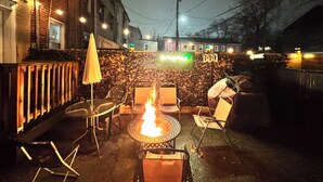 An outdoor patio area with a fire pit, chairs, and a table. There is a sign that reads "BBQ" and a building in the background. - Entire Unit-5min to M&TBank Camden Yards (Baltimore)