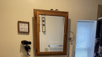 A bathroom with a wooden-framed mirror, a white sink with a faucet, a toilet, and a shower curtain.