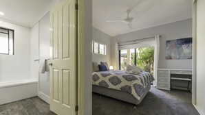 Quarto com cama, escrivaninha, ventilador de teto e janela com persianas.