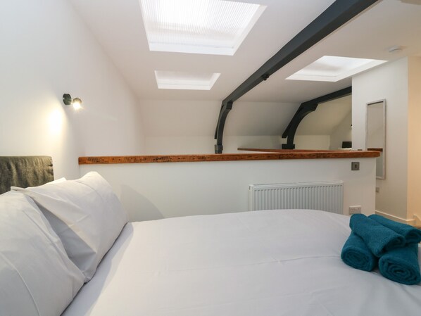 A hotel room with a bed, a skylight, a mirror, and a radiator. - The Dance Hall at The Institute Executive Apartments (Keith)