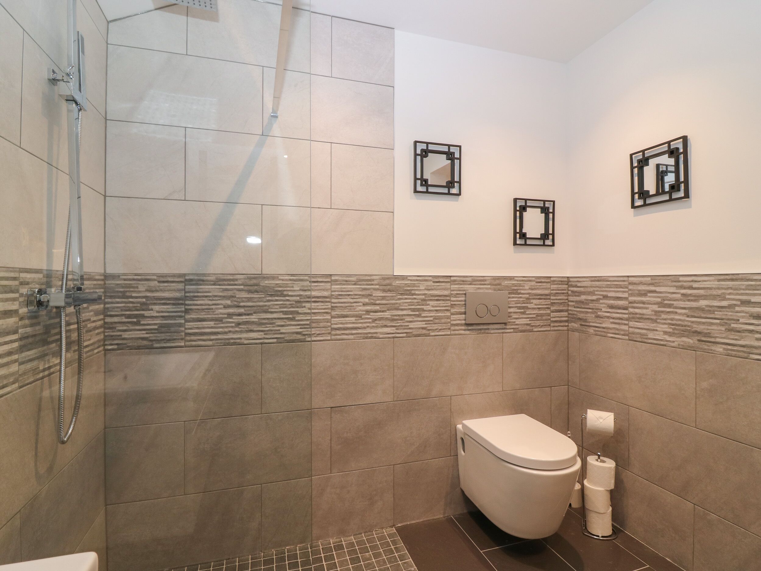 A modern bathroom with a shower, toilet, and two wall-mounted mirrors.