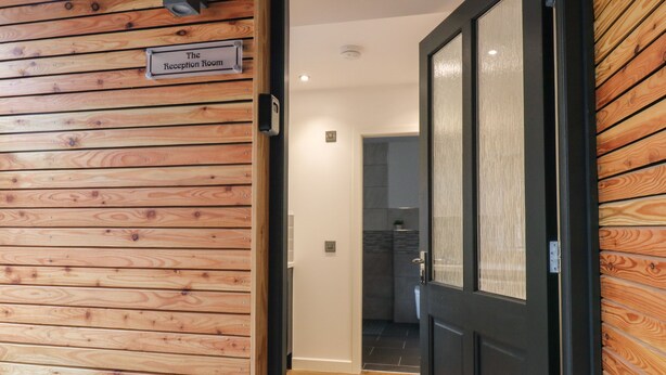 A reception area with a wooden panel wall and a sign indicating it's the reception room. - The Reception Room at The Institute Executive Apartments (Keith)