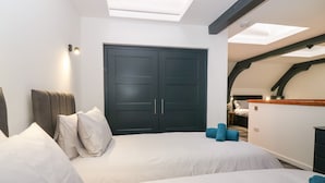 A bedroom with two beds, a wardrobe, and a skylight. - The Reception Room at The Institute Executive Apartments (Keith)