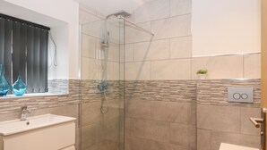A modern bathroom with a glass-enclosed shower, a sink with a mirror, and a toilet. - The Reception Room at The Institute Executive Apartments (Keith)