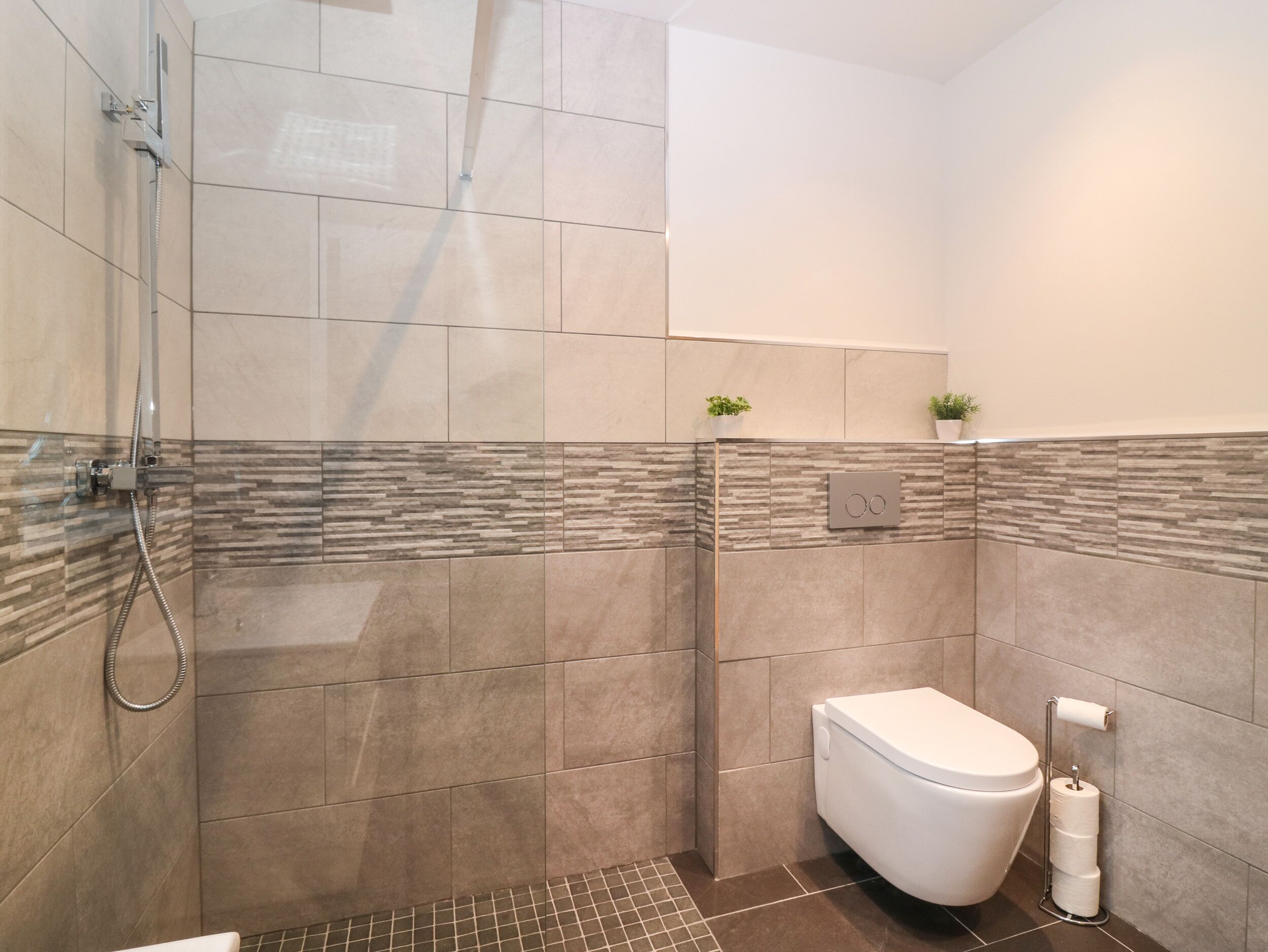 A modern bathroom with a glass-enclosed shower, a toilet, and a towel rack.