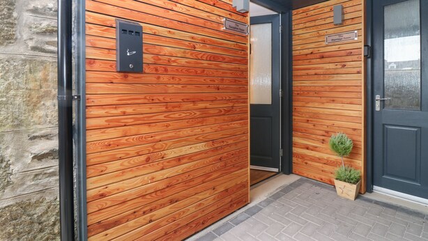 A reception area with a wooden wall, a door labeled "The Reception Room," and a small potted plant. - The Reception Room at The Institute Executive Apartments (Keith)
