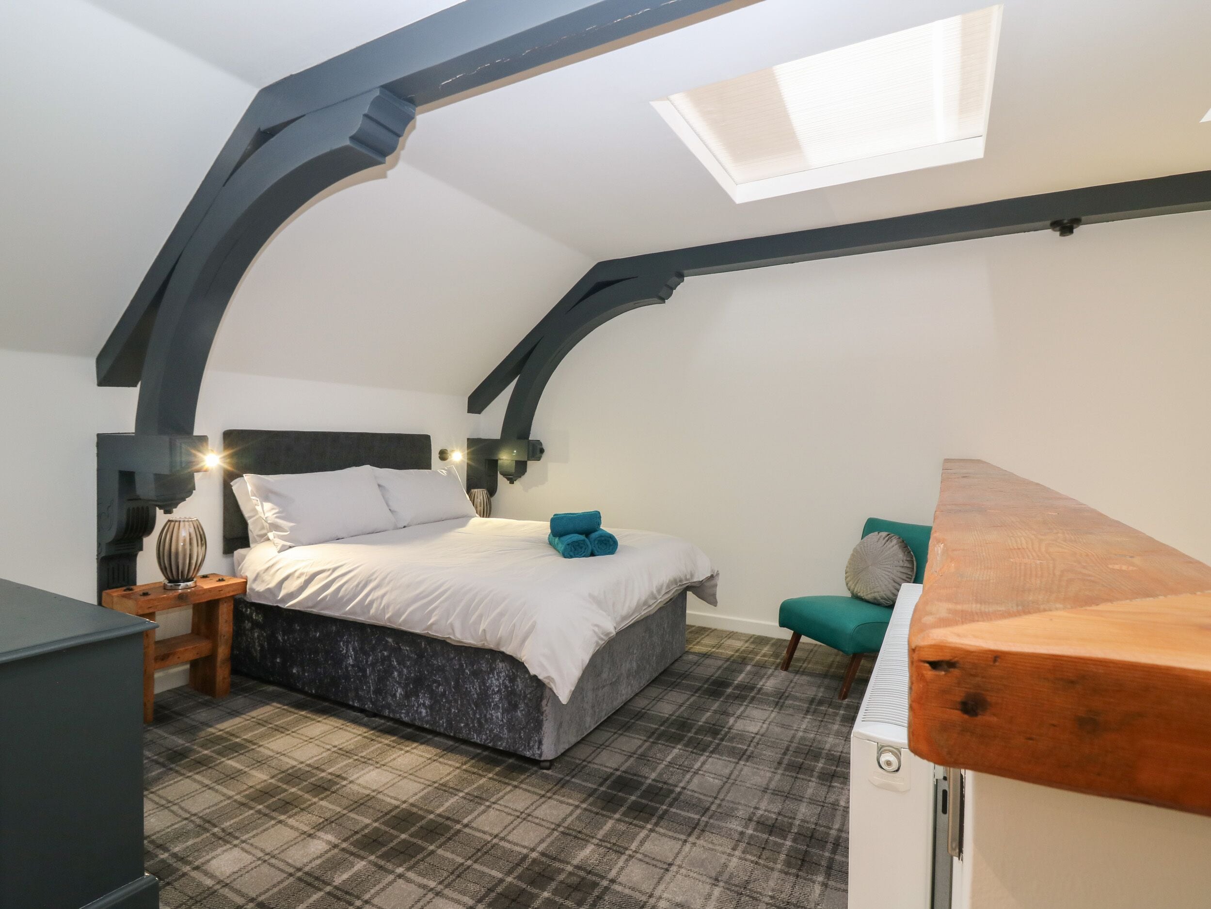 Une chambre à coucher comprenant un lit, une table de chevet, une chaise, une table en bois et une lucarne.
