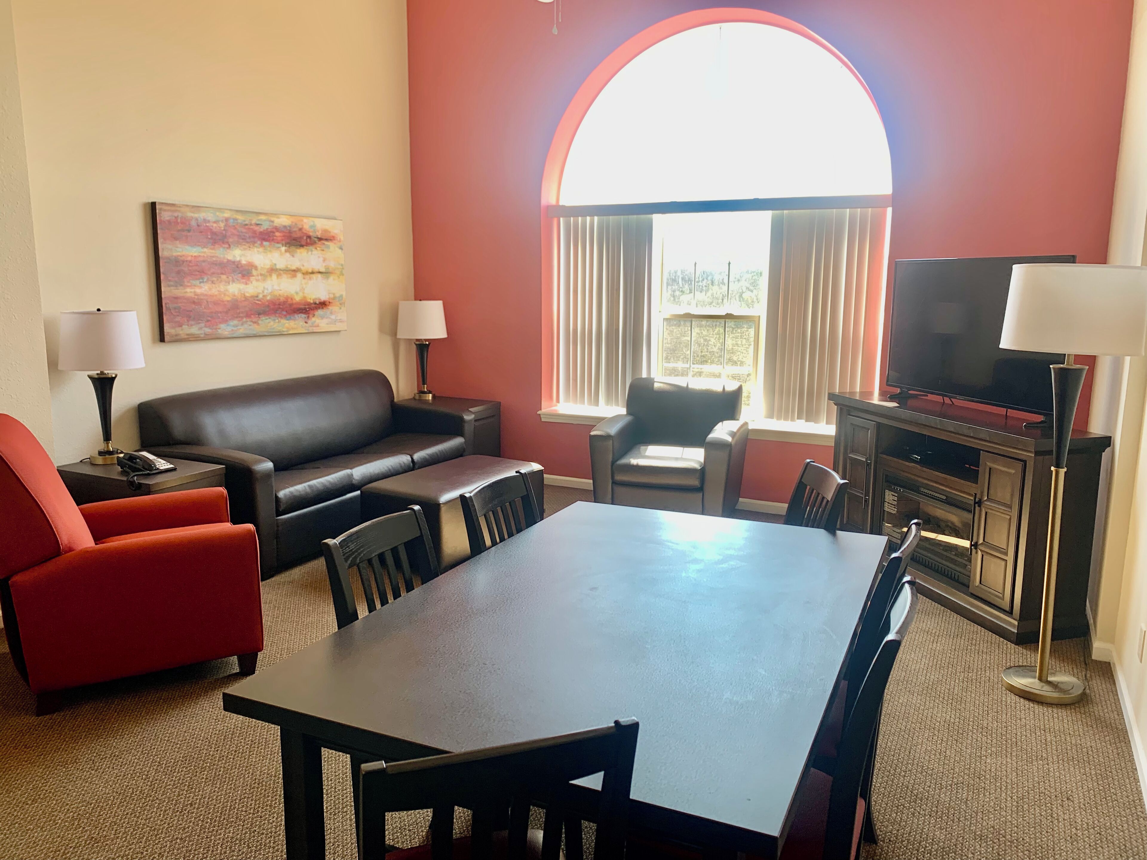 A living room with a sofa, armchairs, a dining table, and a TV.