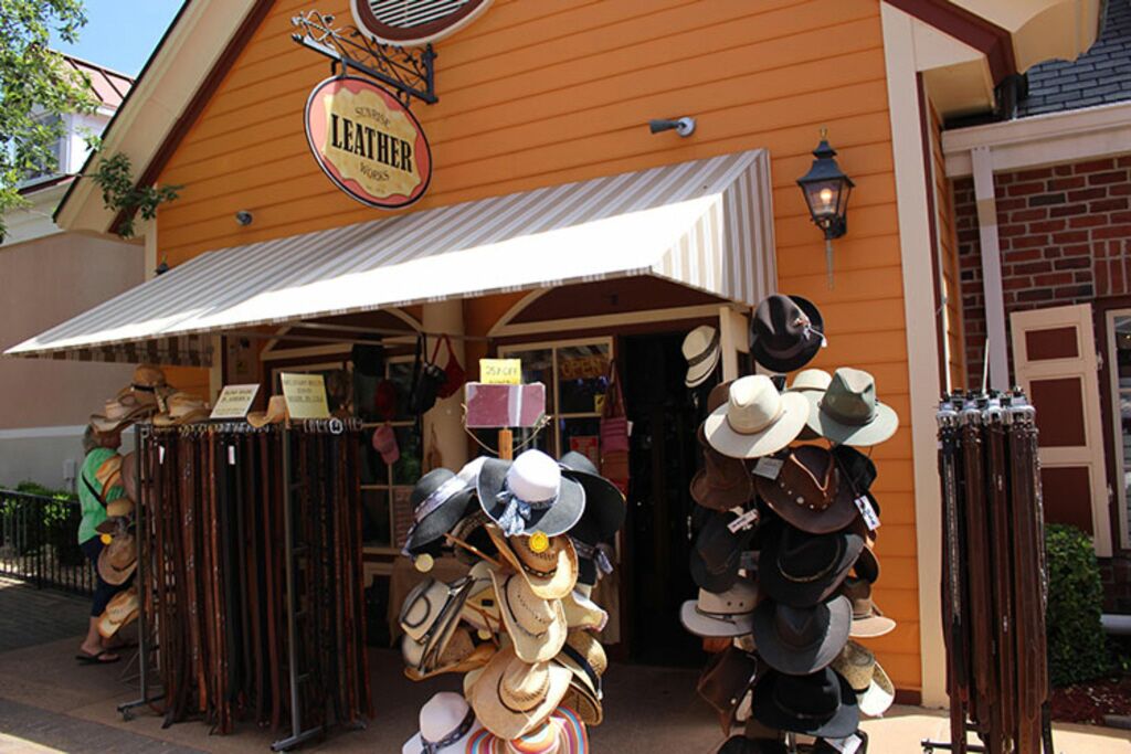 Een winkel met een etalage, een bord waarop 'LEATHER' staat en verschillende hoeden die buiten worden tentoongesteld.